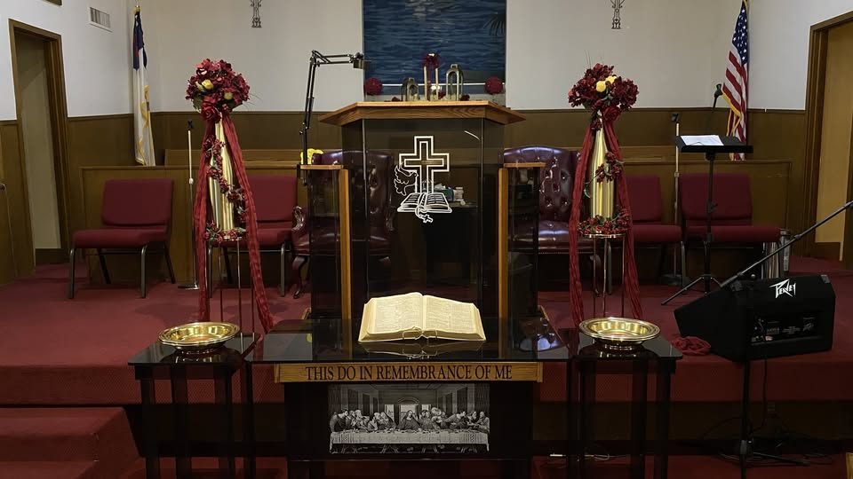 The communion table set beneath the pulpit, with brass plates, an open Bible, and the words This Do In Remembrance Of Me