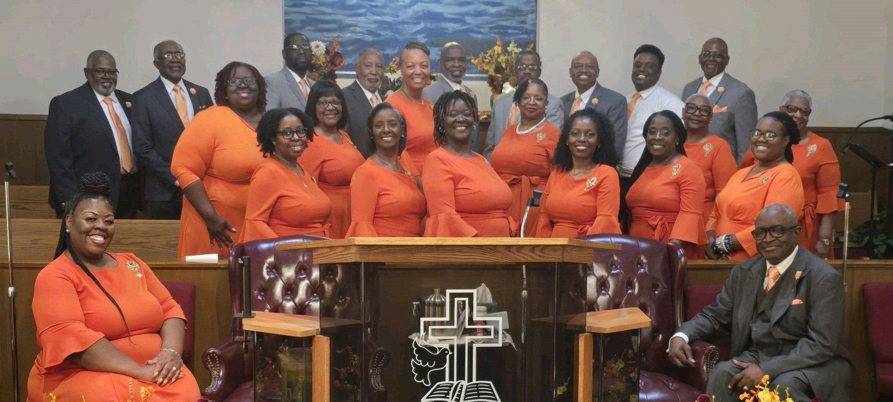 The Mass Choir in orange robes gathered around the pulpit