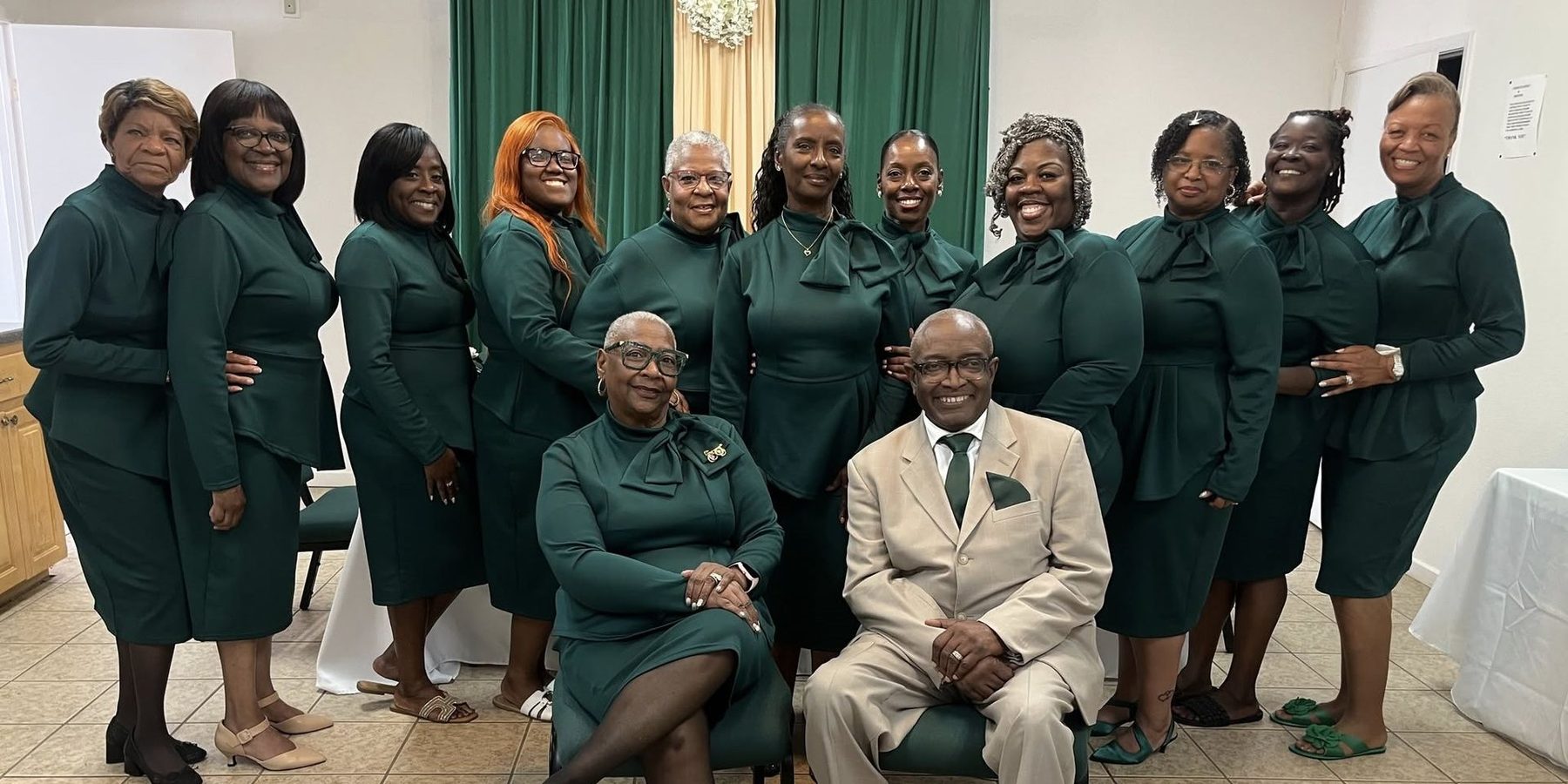The Women Chorus in matching green dresses with Pastor Williams